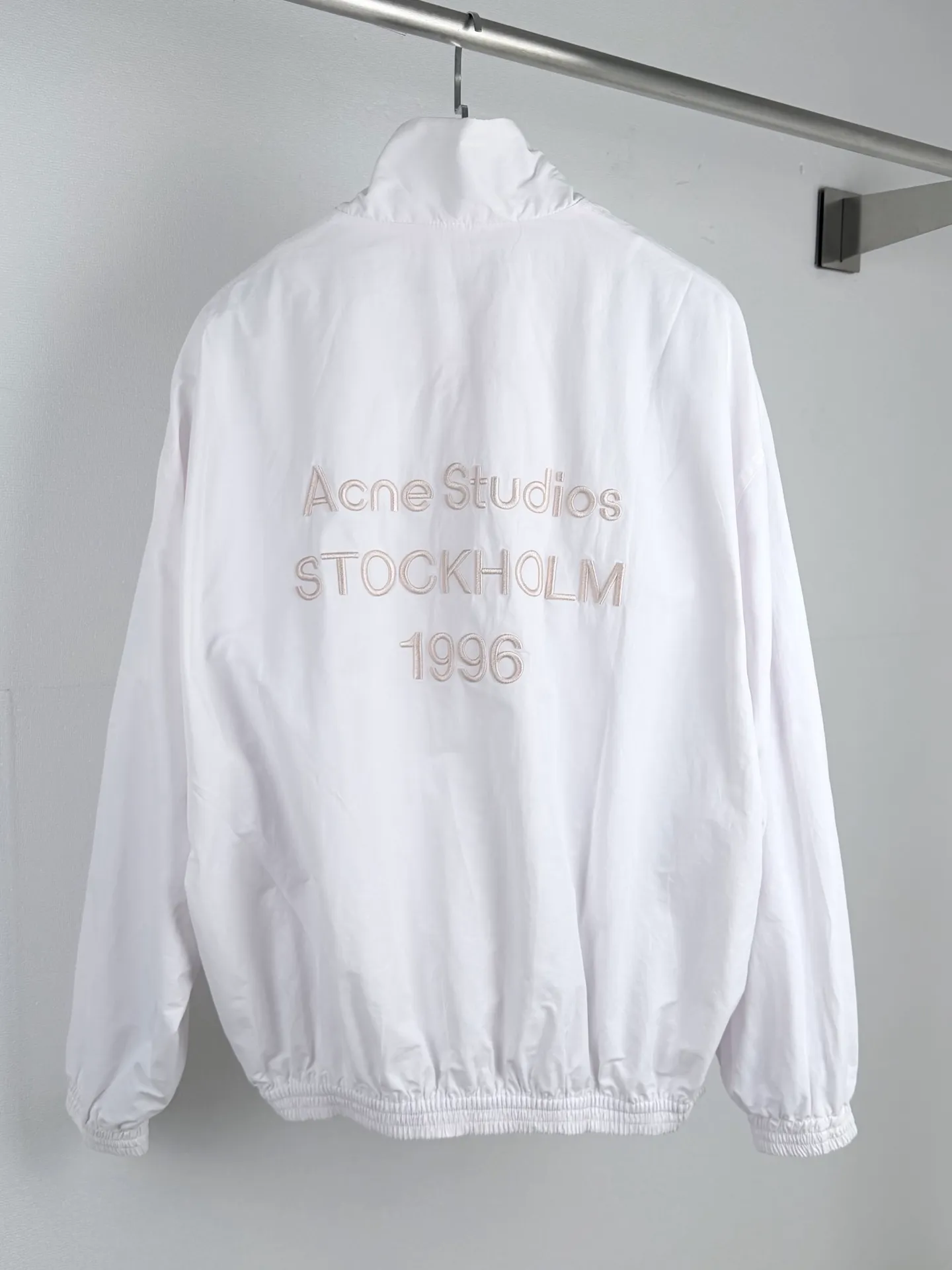 Acne Studios embroidered logo windbreaker jacket. Custom-made Ninglan light woven machine blend. Lightweight and windproof. Stiff and tough. Smoky pink and white calming. It embodies the cool and minimalist Scandinavian aesthetics. Stand-up collar with full zipper for neat opening and closing. Full lining on the inside to improve the smoothness of putting on and taking off. Elastic elasticated precision cuffs at the hem create a relaxed and loose cropped silhouette. Three-dimensional logo embroidery in the same color on the back. Engraved with STOCKHOLM. Chronicle The embroidery is integrated with the body of the garment, hiding the brand's traceability context. The minimalist shape integrates the functional core to interpret the relaxed and relaxed style of high-end ready-to-wear. Process 1: Using imported machine embroidery technology. Using advanced computer control systems and precision mechanical components to realize the Acne Studios logo embroidery operation. High precision. The lines are smooth and delicate. Process 2: The fabrics have been fermented and washed. They have a better hand feel and texture. They are not easy to deform, shrink or fade. Maintain long-term beauty Accessories: Customized 1:1 Acne webbing Customized 1:1 Acne zipper Customized 1:1 Acne trademark Version: Loose version Size: 44 46 48 50
